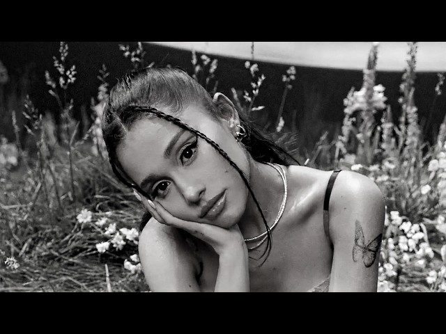 Ariana Grande sitting among wildflowers in black and white promotional photo for petal